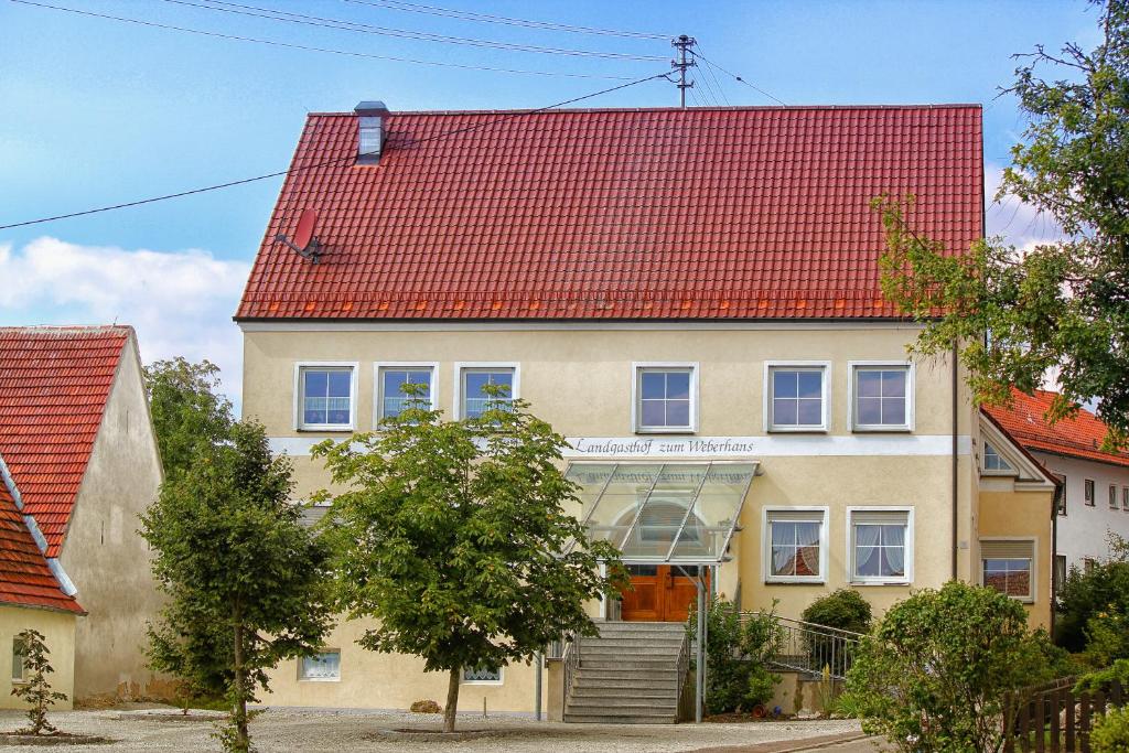 ein großes Haus mit rotem Dach in der Unterkunft Landgasthof Weberhans in Harburg