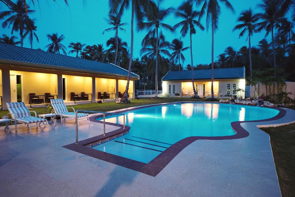 a swimming pool in front of a house with palm trees at Coco Cabana Apartelle in Panglao