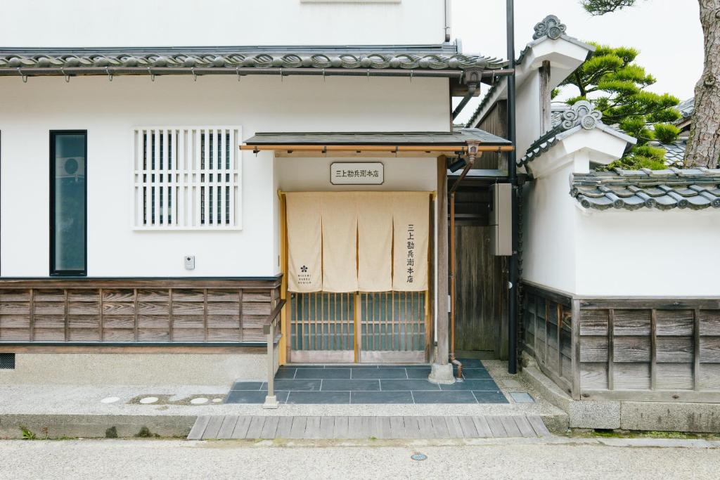 un bâtiment avec une porte munie d'un panneau. dans l'établissement 三上勘兵衛本店 Mikami Kanbe Honten, à Miyazu