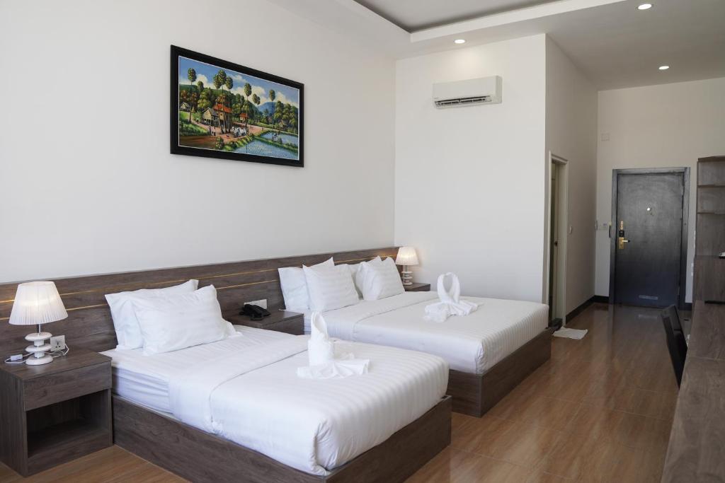 um quarto de hotel com duas camas e uma foto na parede em Apple Hotel Three - near PNH airport em Phnom Penh