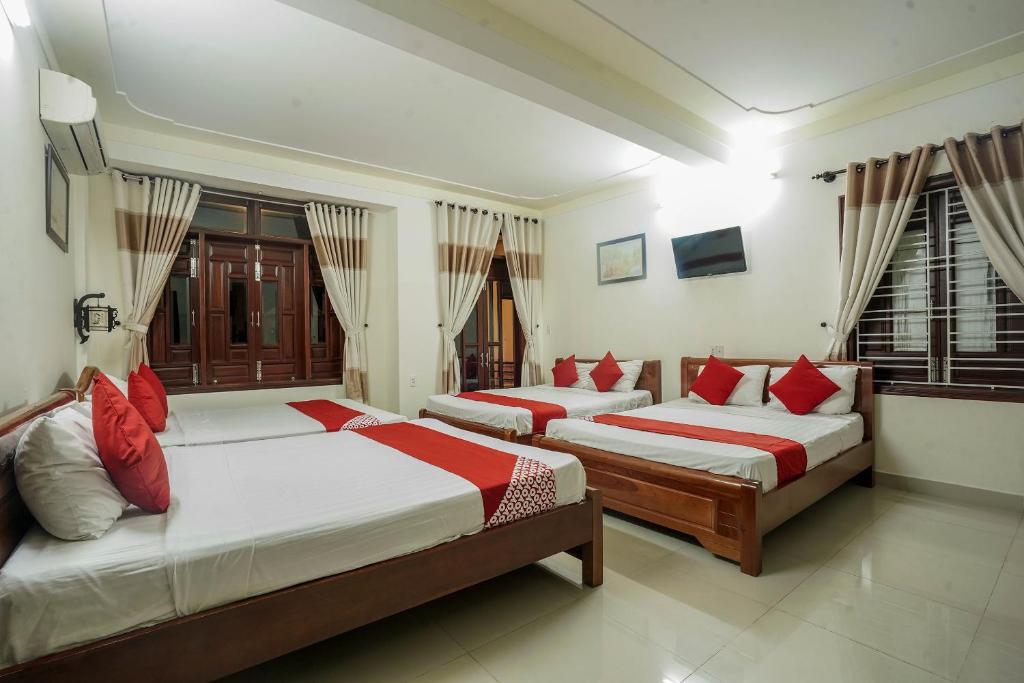a bedroom with two beds with red pillows at Windy River Homestay in Hoi An