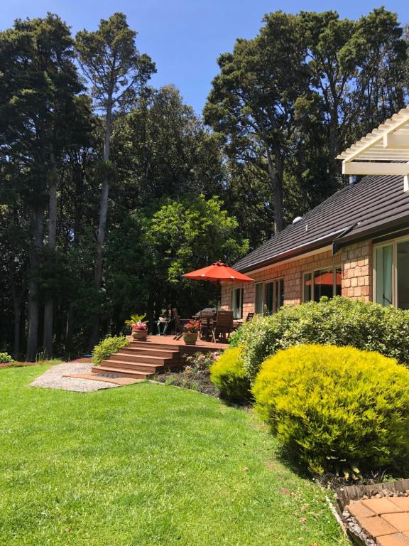 a house with a patio with a table and an umbrella at N.Z Country Home in Whangarei