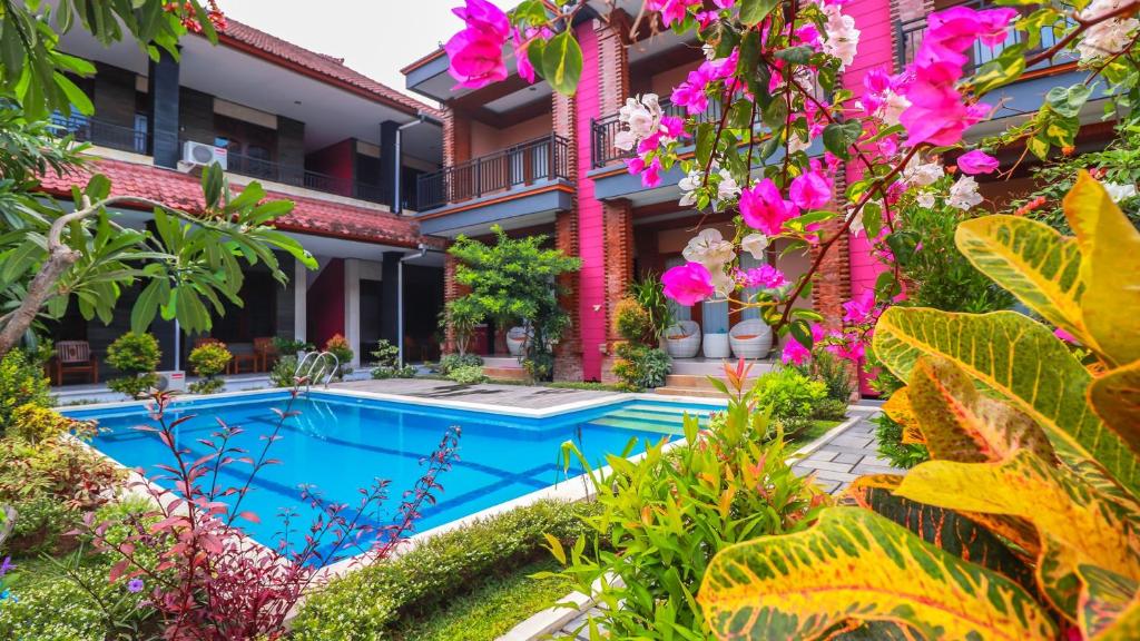 a garden with a swimming pool in front of a building at Mia Guest House in Legian