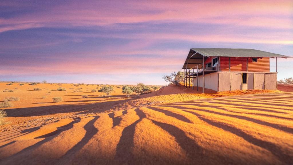 Ein Haus mitten in einer Wüste mit Schatten in der Unterkunft Bagatelle Kalahari Game Ranch in Hardap