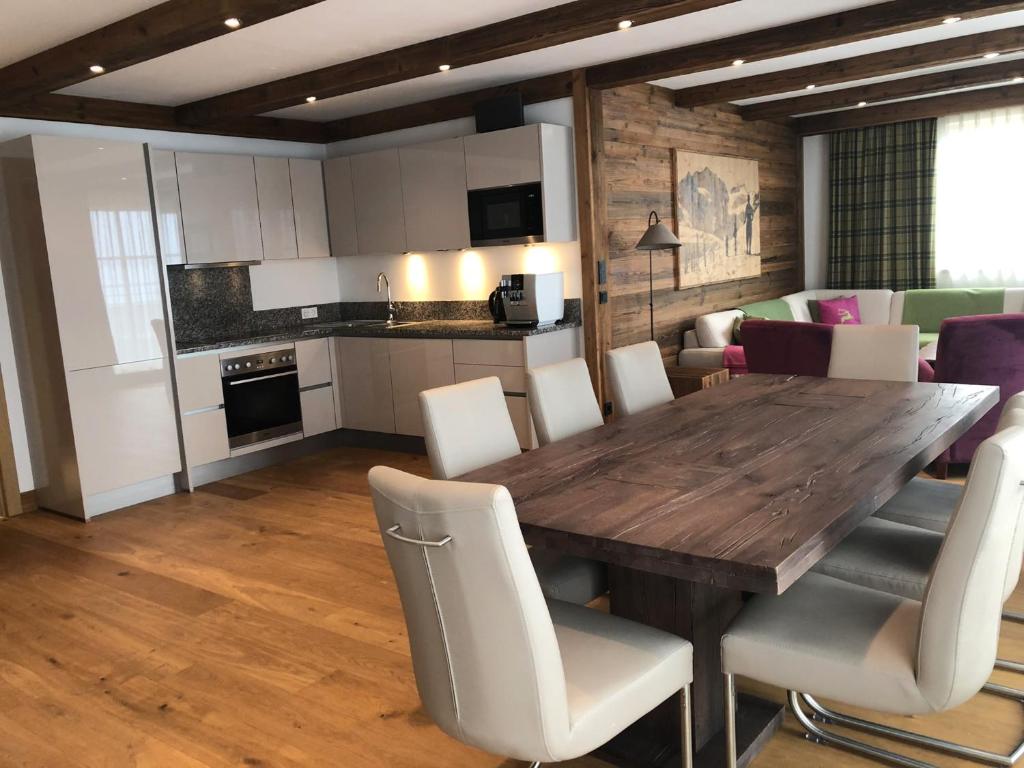 a kitchen and dining room with a wooden table and chairs at The LODGE, Saalbach in Saalbach-Hinterglemm