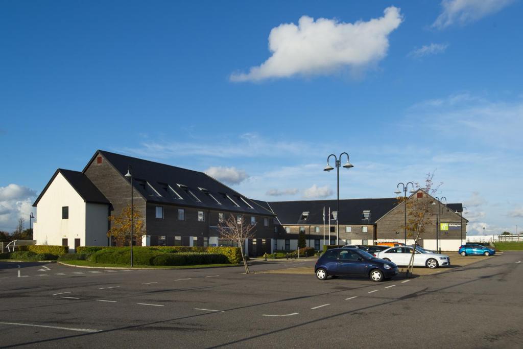 um parque de estacionamento com carros estacionados em frente a um edifício em Holiday Inn Express London - Epsom Downs, an IHG Hotel em Epsom