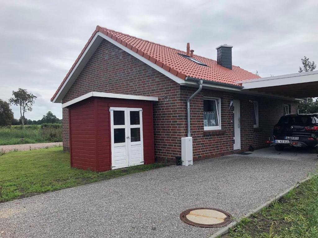 una casa de ladrillo rojo con un coche aparcado en la entrada en Ferienhaus Wattkieker, en Sehestedt