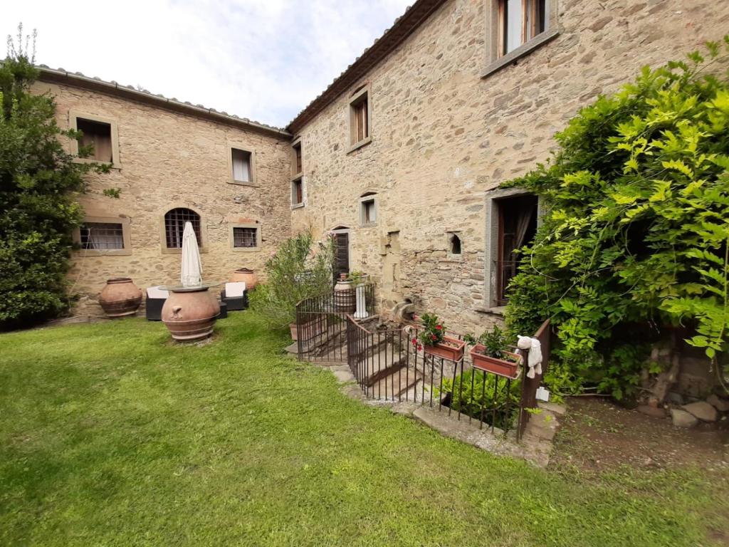 un gran edificio de ladrillo con un patio con una valla en Agriturismo Frantoio Valiani, en Cortona