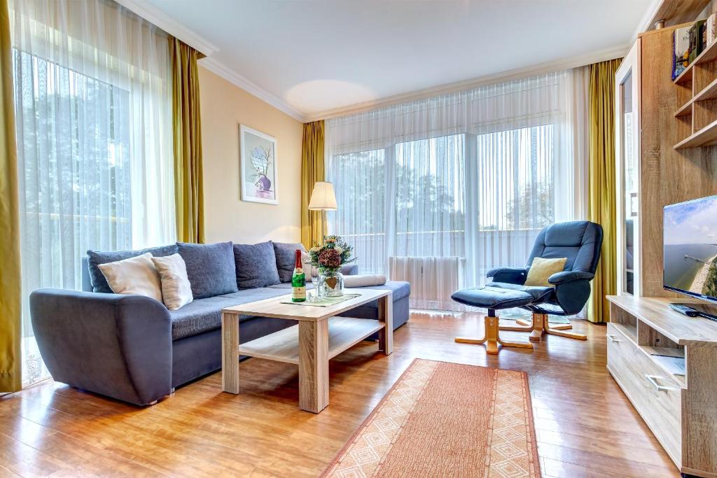 een woonkamer met een blauwe bank en een tafel bij Am Schloonsee Haus D in Heringsdorf