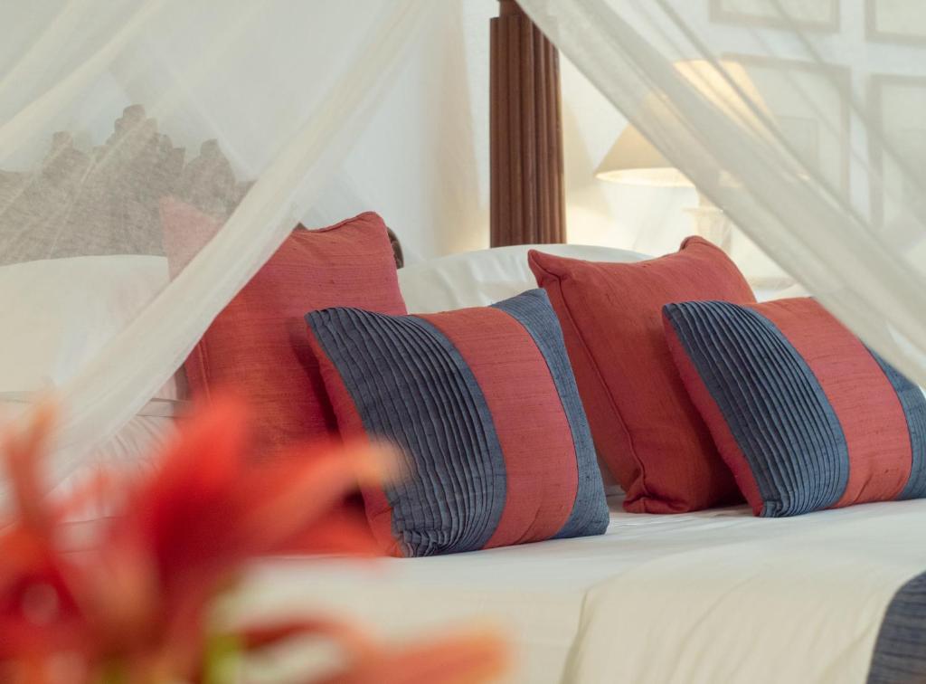 a bed with red and blue pillows on it at Le Colonial 1506 - Exclusive Luxury Hideaway in Cochin