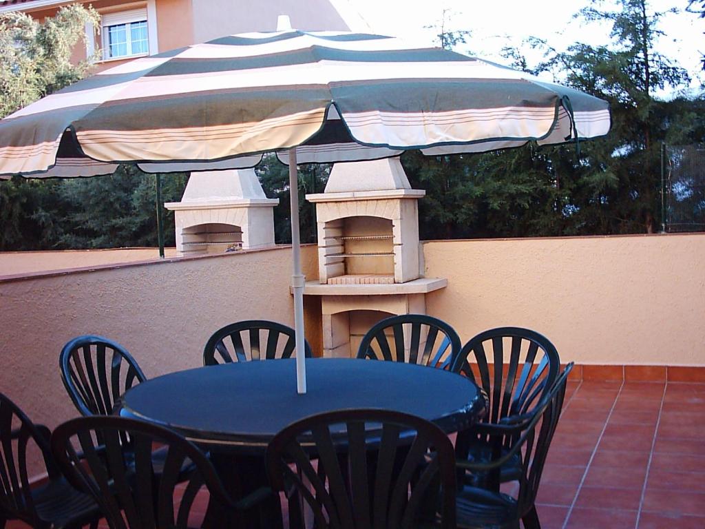 einen blauen Tisch und Stühle mit Sonnenschirm auf einer Terrasse in der Unterkunft Parque Sierra Norte in Rascafría