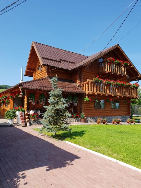 a log house with flowers on the front of it at Cabana Popasul Calaretului in Râşnov