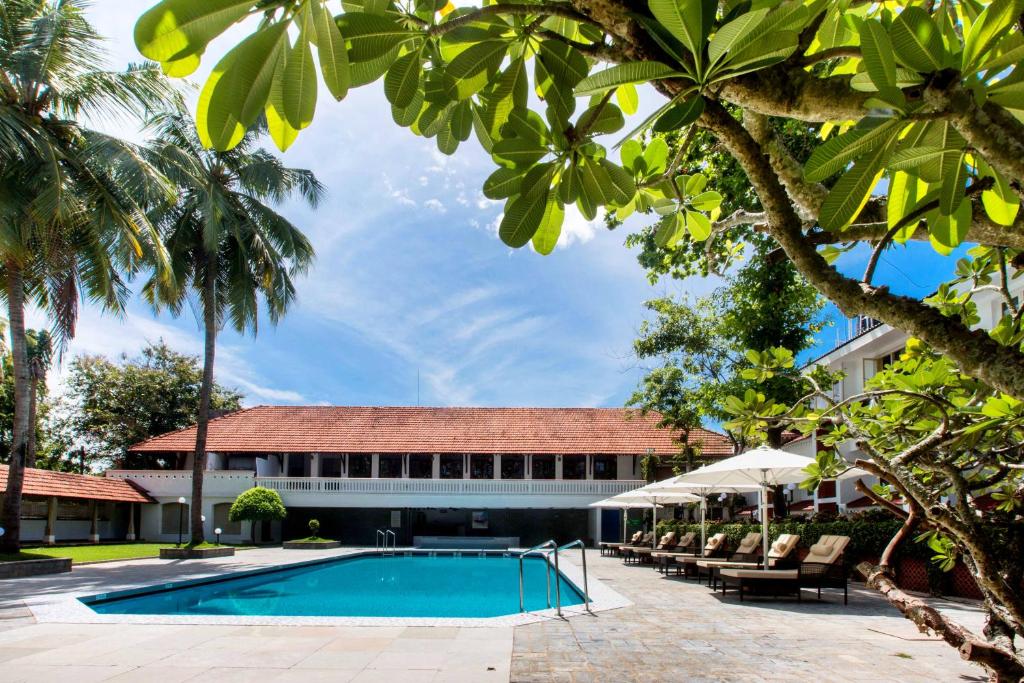 - une piscine en face d'un bâtiment avec des palmiers dans l'établissement Casino Hotel - CGH Earth, Cochin, à Cochin