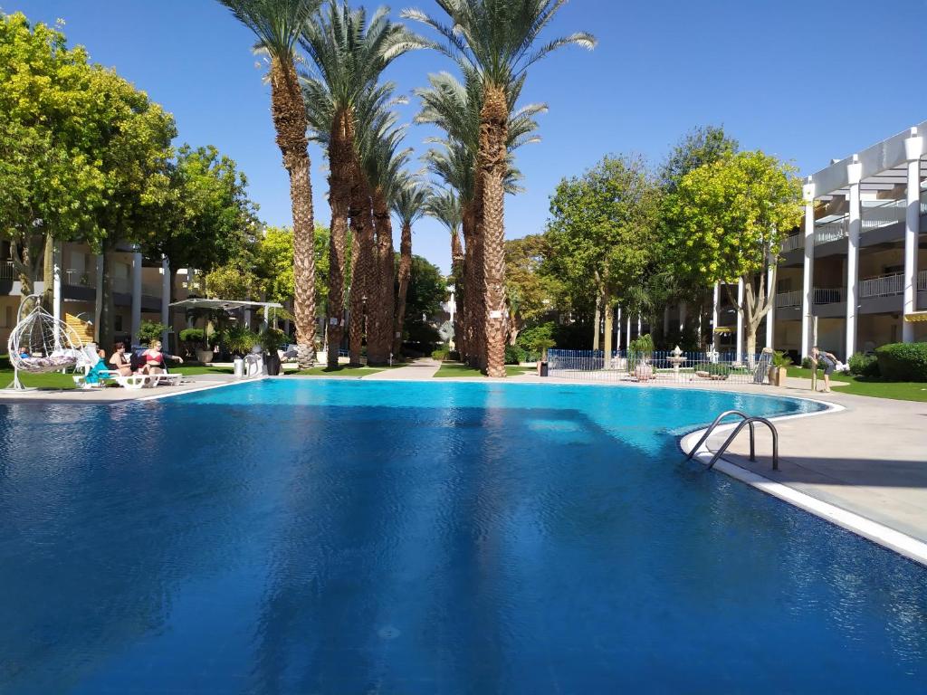 een groot blauw zwembad met palmbomen bij Bari suite at Royal Park in Eilat