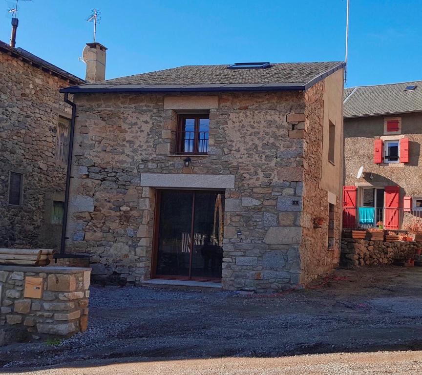 un edificio de piedra con una puerta a un lado en Grange de caractère en pierre al badiu, en La Llagonne