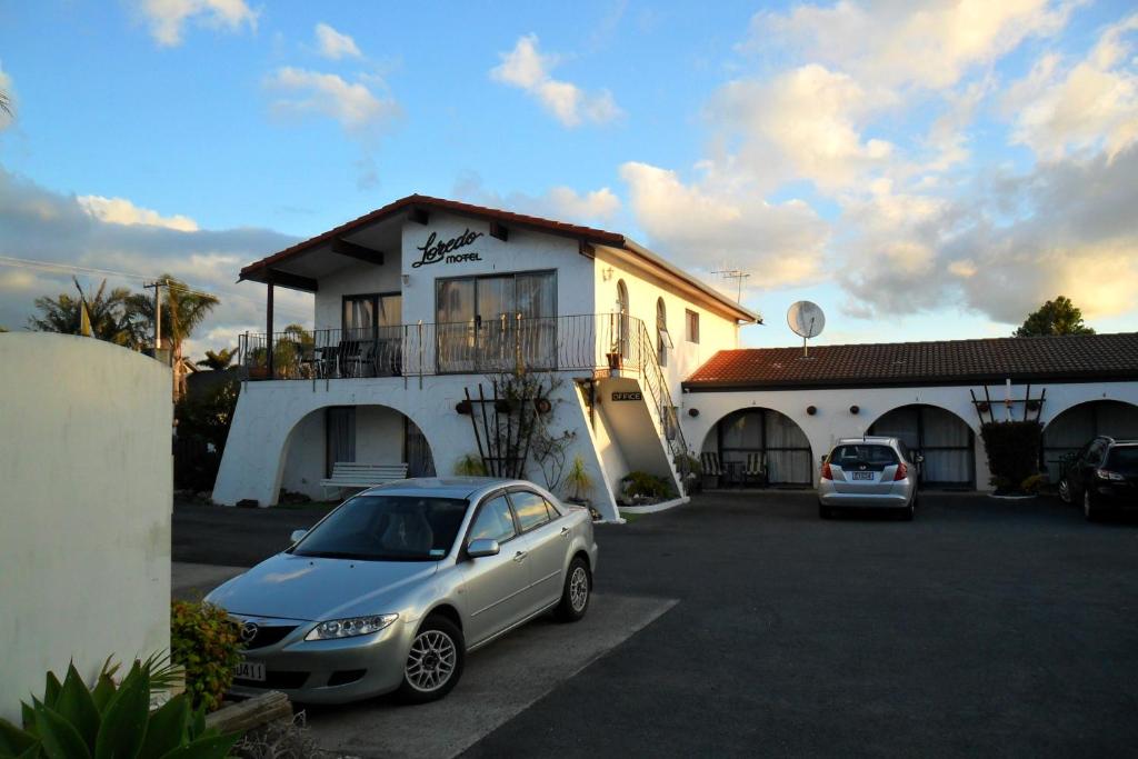 two cars parked in a parking lot in front of a building at Loredo Motel in Kaitaia