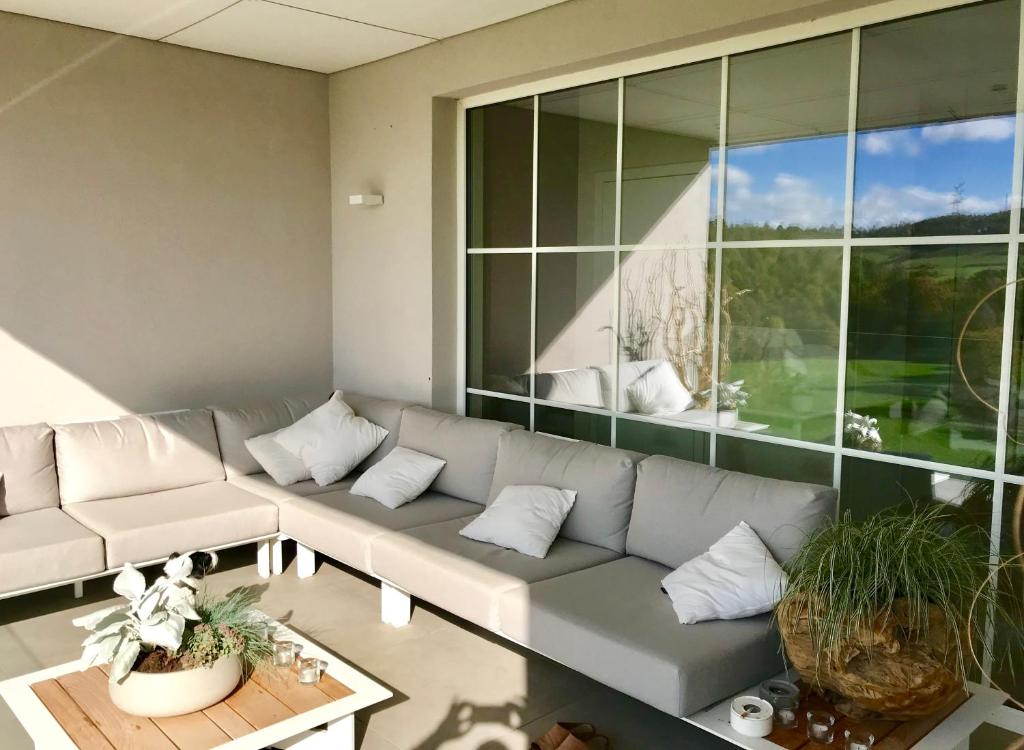 a living room with a couch and a large window at L'Auf der Tomm in Martelange