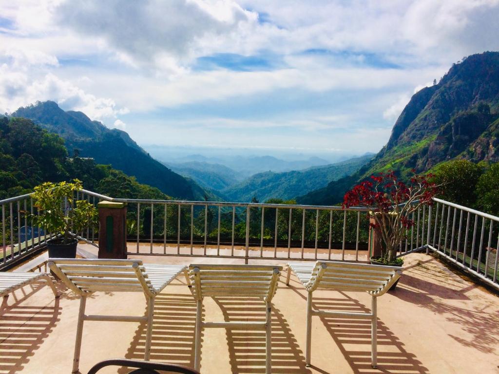 three chairs sitting on a balcony overlooking a valley at Hilltop Guest House in Ella