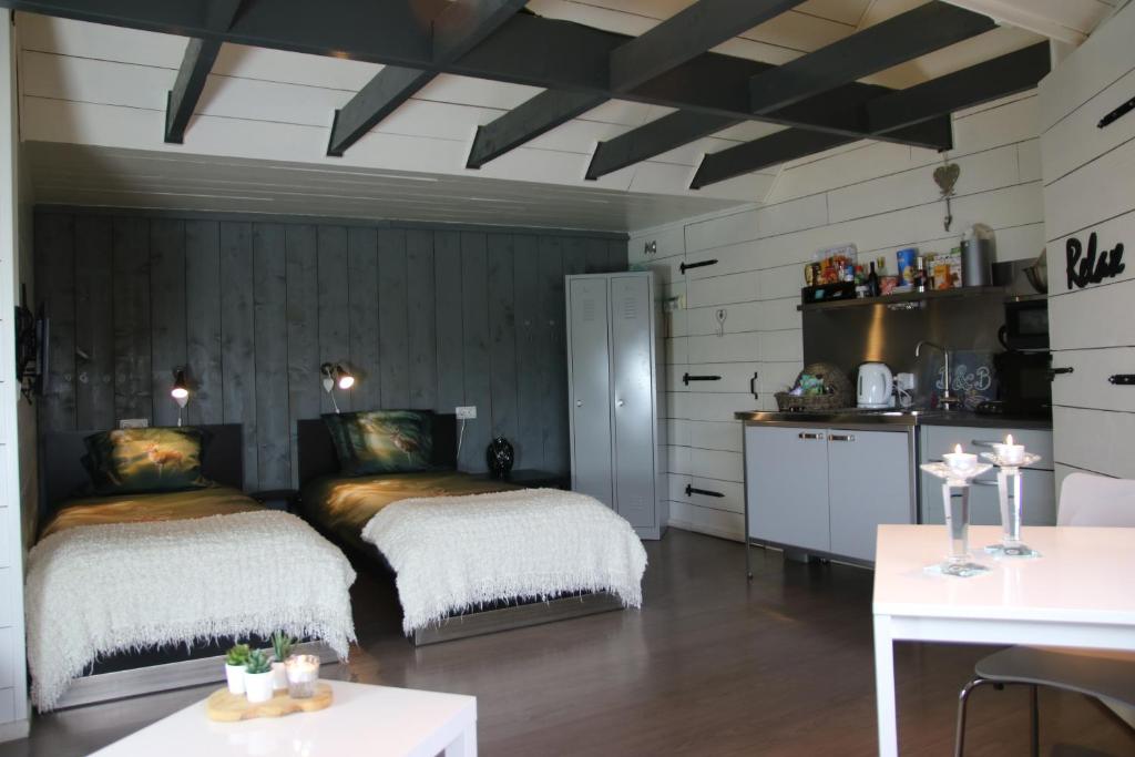 two beds in a room with a table and a kitchen at B&B in de Dorpsstraat in Hellendoorn