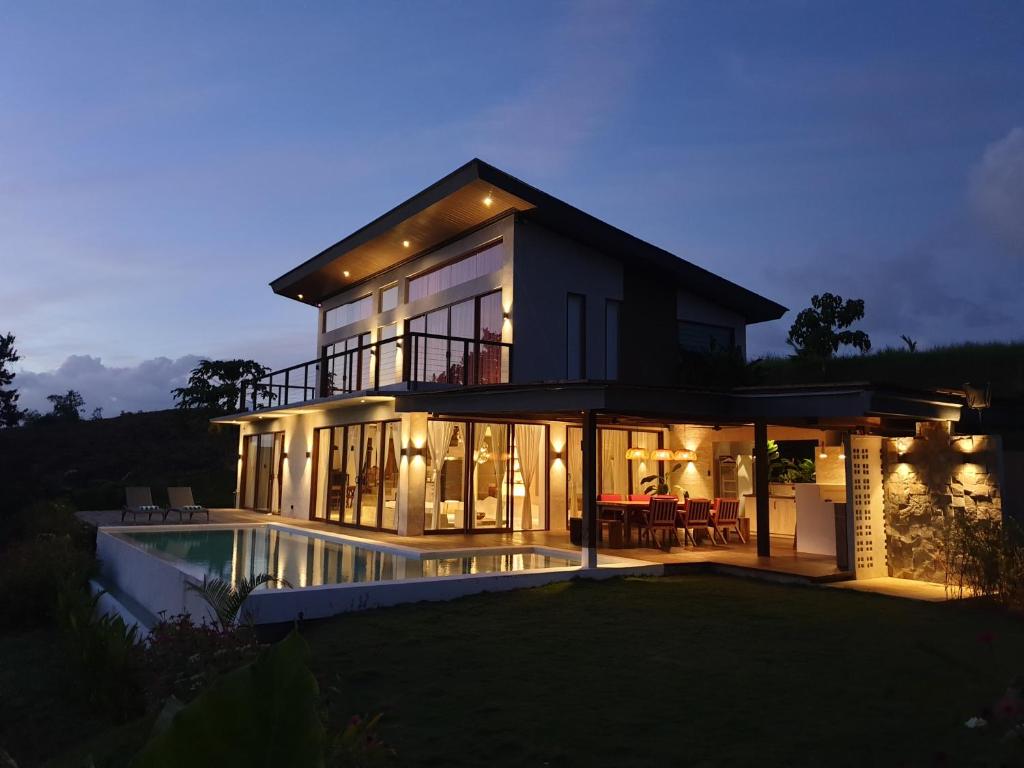 een groot huis met een zwembad in de nacht bij Mango Tree Siargao in General Luna