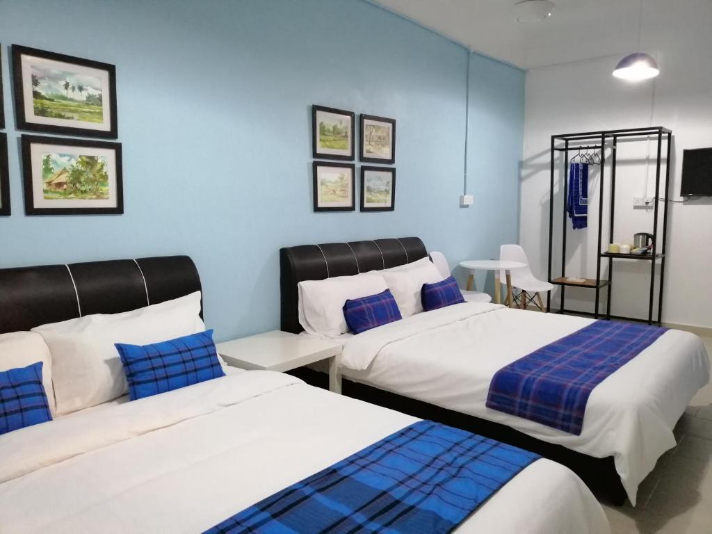 2 Betten in einem Zimmer mit blauen Wänden in der Unterkunft Teriang Village Inn in Kampung Padang Masirat