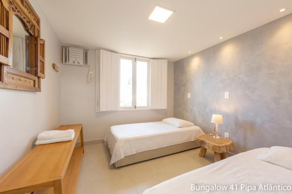 Un dormitorio con dos camas y una ventana. en Pipa Atlântico Bungalow 41, en Pipa