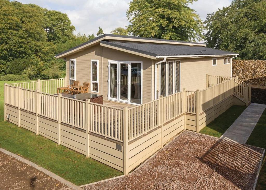 a tiny house with a large deck in a yard at Alder Country Park in North Walsham