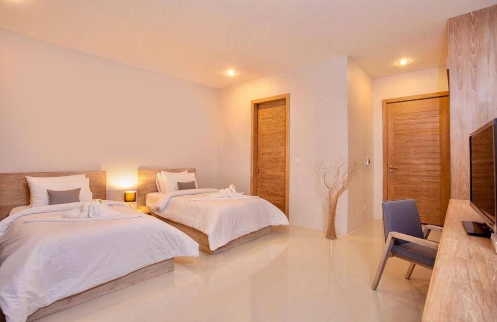 a bedroom with two beds and a television in it at Lemonade Phuket Hotel -SHA Plus in Chalong