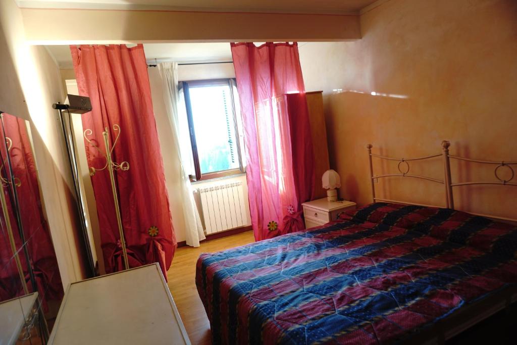 Affitta camere San Miniato في سان مينياتو: غرفة نوم بسرير وستائر حمراء ونافذة
