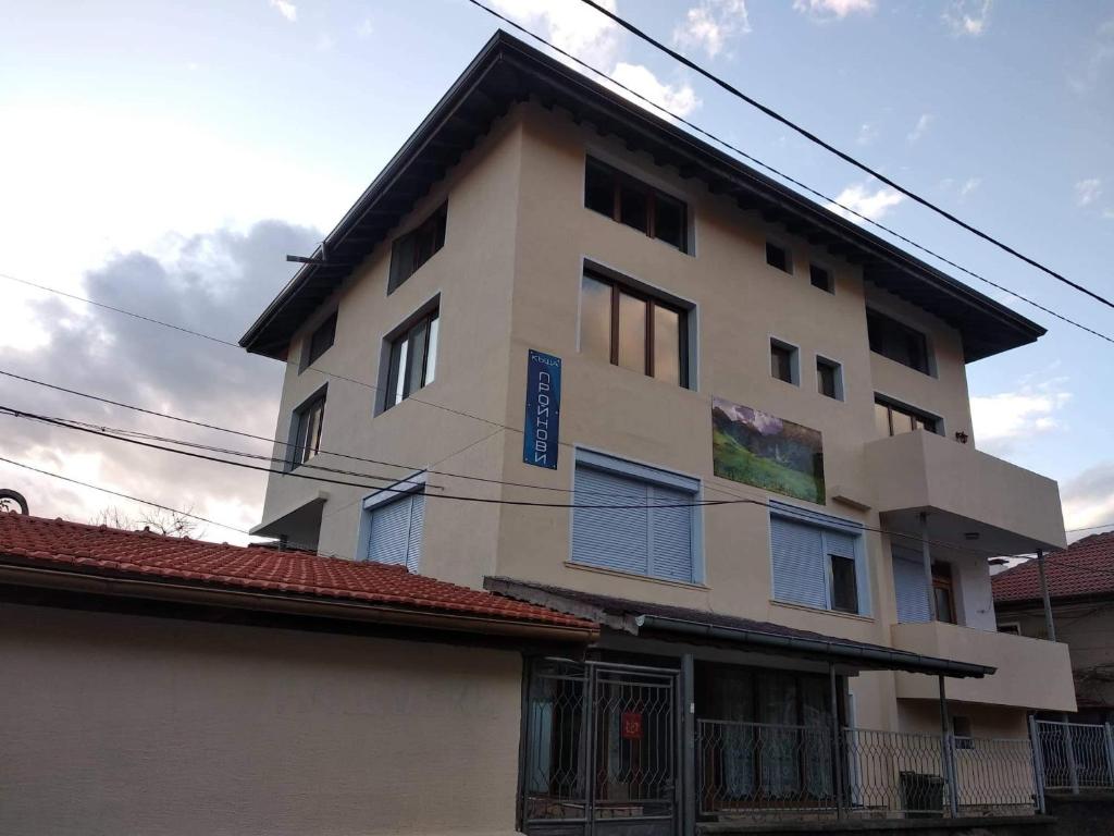 een wit gebouw met blauwe ramen aan de zijkant bij Guest House Proynovi in Kalofer