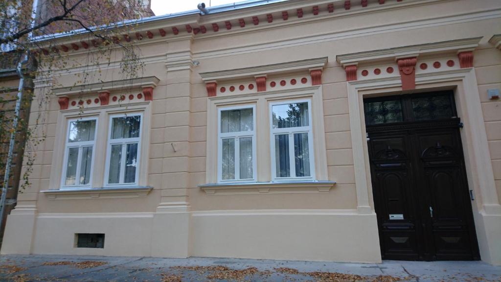un edificio con una puerta negra y dos ventanas en Konzul, en Osijek