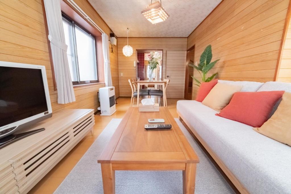 een woonkamer met een bank en een tv bij Nakajima Park West House / Vacation STAY 5418 in Sapporo