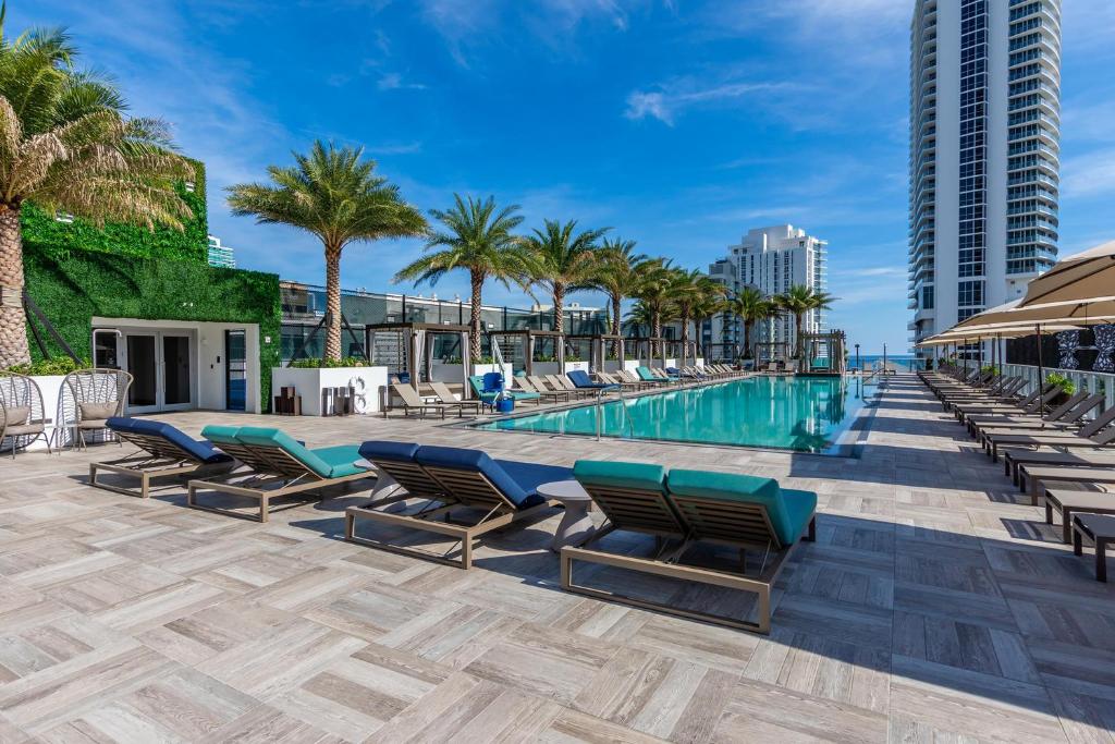uma piscina com espreguiçadeiras e palmeiras em Amazing Apartments at H Beach House em Hollywood