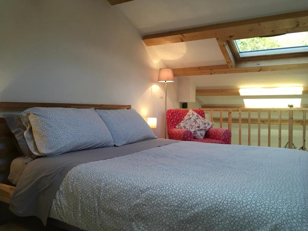 a bedroom with a bed and a red chair at La casa di Julie in Ronchi dei Legionari