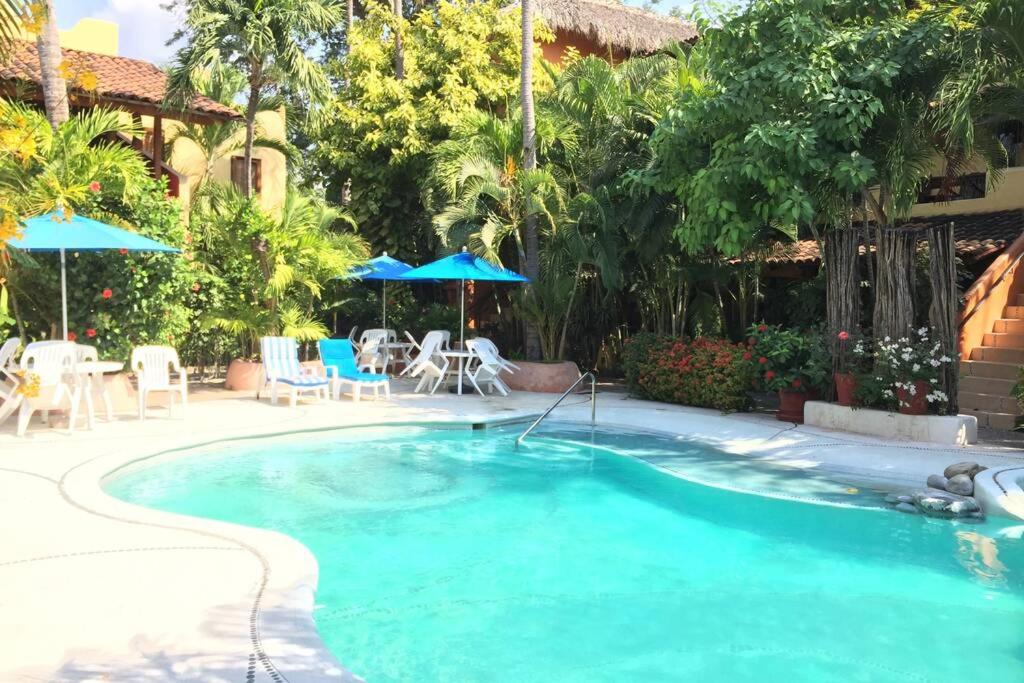 a pool at a resort with chairs and umbrellas at Newer & Roomy w/2 Pools. No Car Needed. Beaches, Restaurants & Shopping W/I walking distance. Taxis and buses abundant for reasonable price if needed in Zihuatanejo