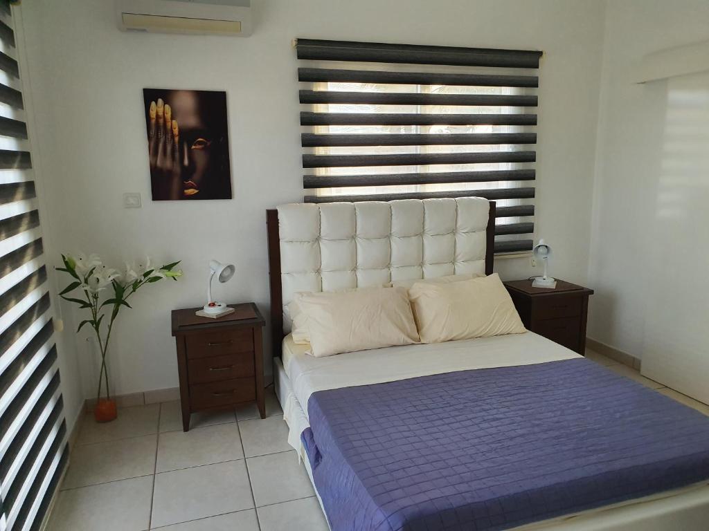 a bedroom with a bed and two tables and a window at A- Luxury Sea Villa next to the beach in Ayia Napa