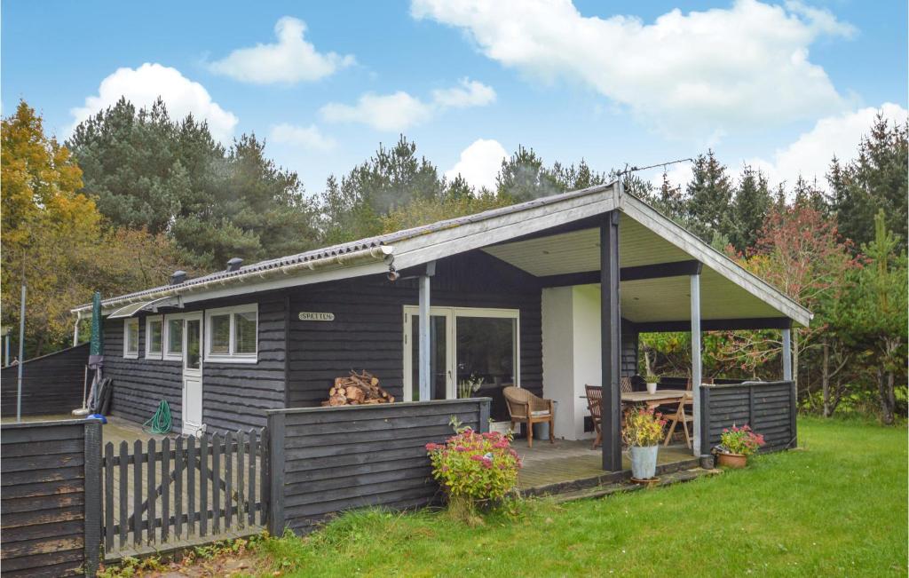 een zwart huisje met een veranda en een hond op de veranda bij Sptten in Brovst