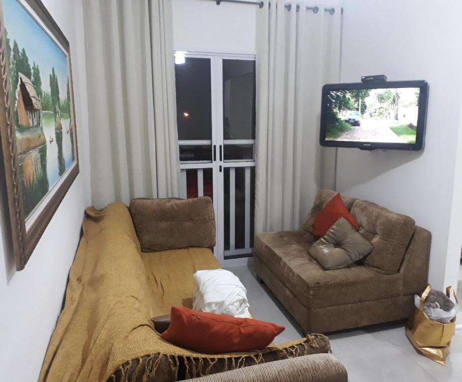 ein Wohnzimmer mit einem Sofa und einem TV in der Unterkunft Jd das Palmeiras in Ubatuba