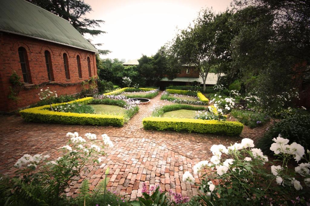 a garden with bushes and flowers on a brick path at Kings Grant Country Retreat in Ixopo