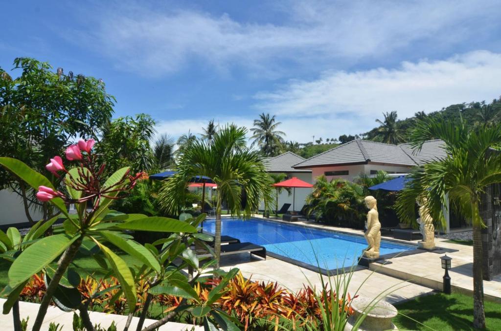 a resort swimming pool with palm trees and a house at Dream Estate Resort in Senggigi