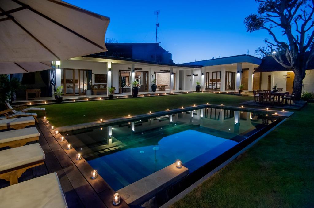 a swimming pool in the backyard of a house at night at RUMAH WAYAN ULUWATU in Uluwatu