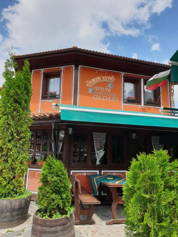 un edificio arancione con un tavolo da picnic di fronte di Chuchura Family Hotel a Koprivshtitsa