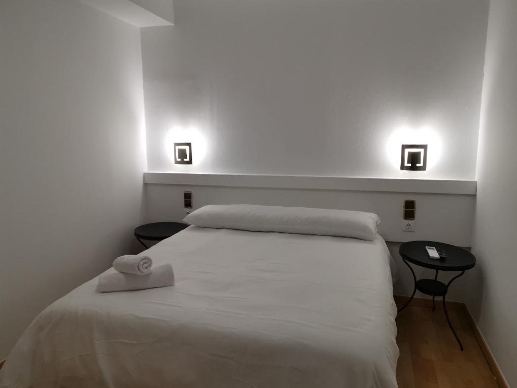 1 dormitorio con 1 cama blanca con 2 mesas y 2 luces en Hostal Quinta Santillan en San Fernando de Henares