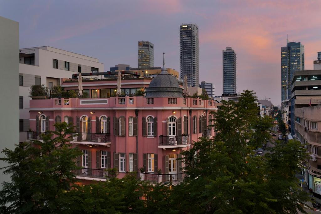 a pink building in front of a city at Hotel Nordoy in Tel Aviv