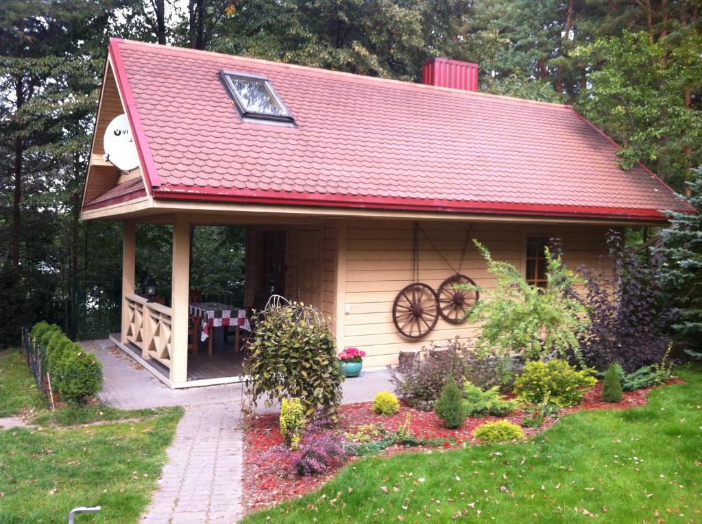 una pequeña casa con techo rojo en un patio en Medaus pirtelė en Trakai