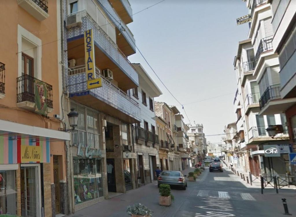 una calle de la ciudad con edificios y coches aparcados en la calle en Hostal Residencia Pasaje en Novelda