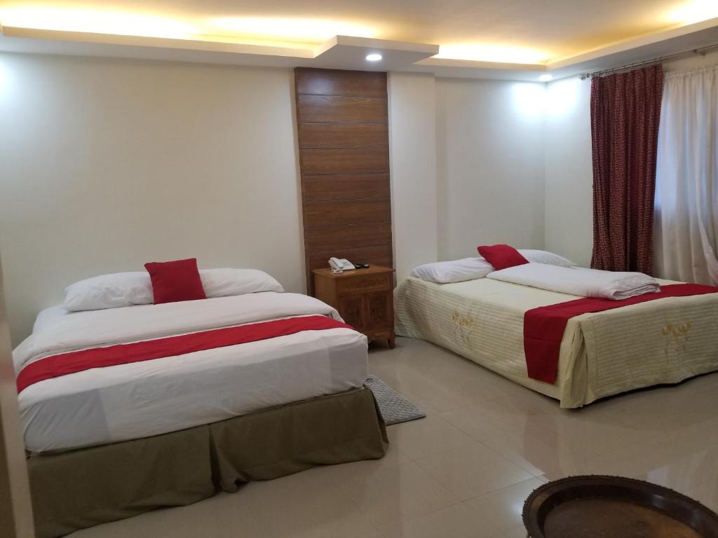 a bedroom with two beds with red and white sheets at La Anclar Hotel in Davao City