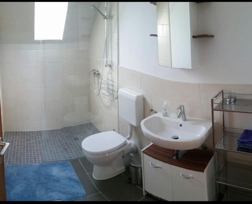 Łazienka z białą toaletą i umywalką w obiekcie Ferienwohnung Heuer w mieście Fehmarn