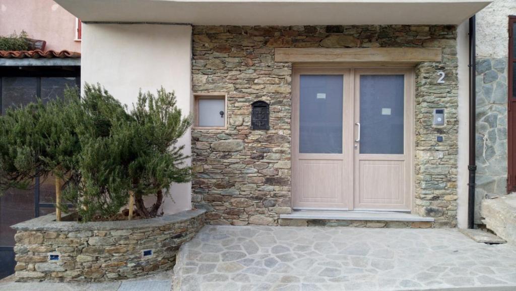 una porta d'ingresso di una casa in pietra con un albero di Ca' Nova a Roccaforte Mondovì