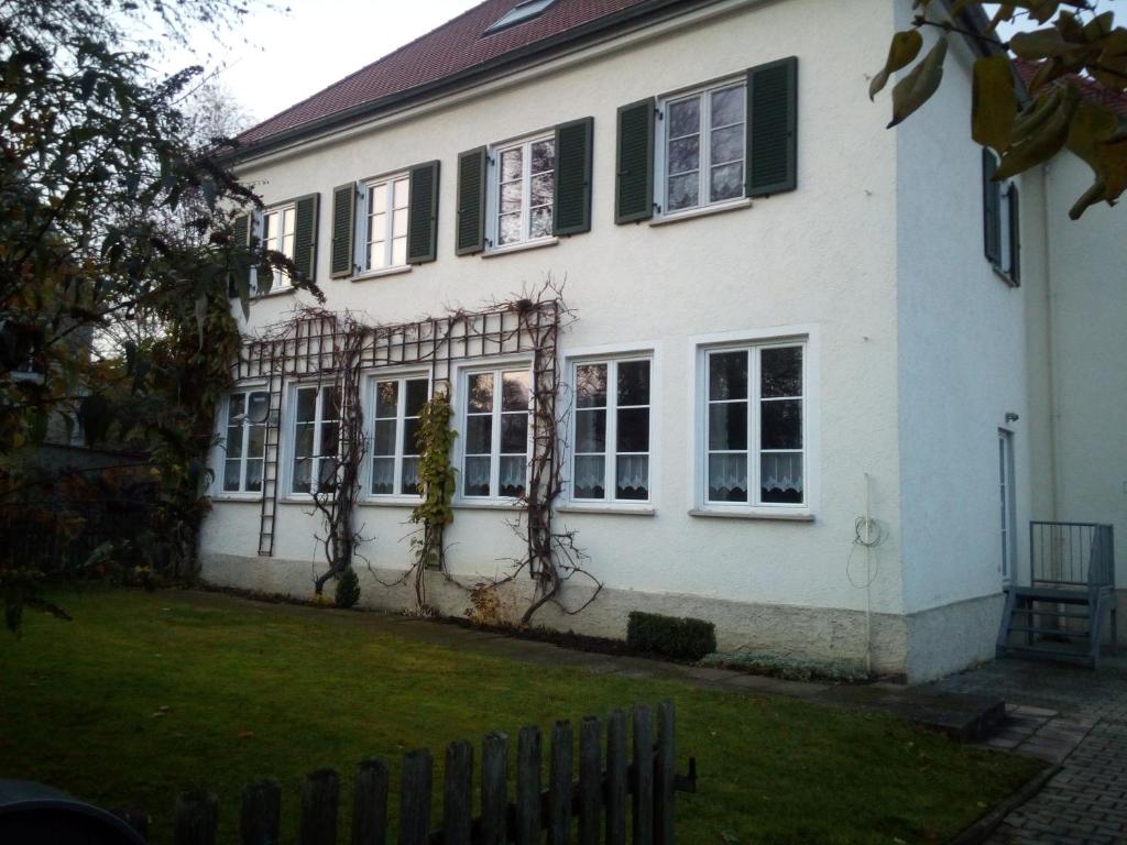 une maison blanche avec des volets verts et une cour dans l'établissement Ferienwohnung Kopold "Im alten Schulhaus", à Pöttmes